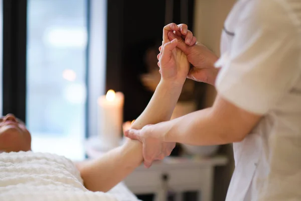Masaż nadgarstka. masażystka wywiera nacisk na czuły punkt dłoni kobiety. Fizjoterapeutka masująca dłoń swoich pacjentów w gabinecie medycznym — Zdjęcie stockowe