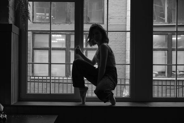 Černobílá fotka tanečnice v okenním rámu ve staré budově. Mladá, elegantní, půvabná baletka — Stock fotografie