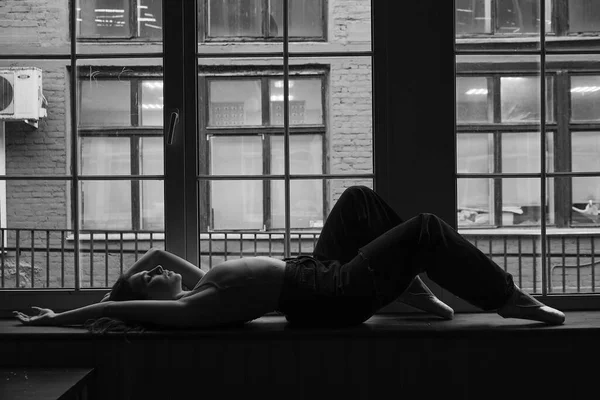 Черно-белая фотография танцовщицы в оконной раме в старом здании. Молодая, элегантная, изящная балетная балерина — стоковое фото