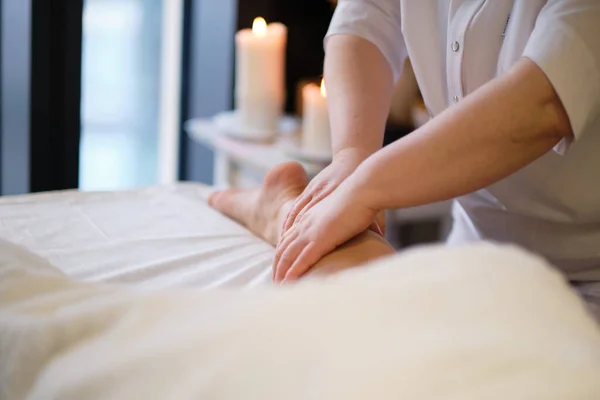 Detail van handen masseren menselijke kuitspier Therapeut uitoefenen druk op vrouwelijke been. Handen van massage therapeut masseren benen van jonge vrouw in spa salon. Lichaamsverzorging in spa salon voor jonge vrouw. — Stockfoto