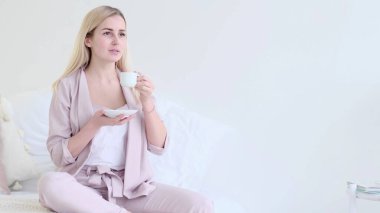 Romantik bir ortamda bir fincan kahveyle güzel genç bir kadın. Kahve fincanı olan, kanepeye oturmuş kameraya bakan kadın. seçici odak.