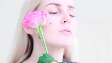 Narin gül çiçeğiyle güzel bir genç kadın. Temiz, taze bir kız yüzüne çiçeklerle dokunuyor. yumuşak odaklı, seçici odaklı