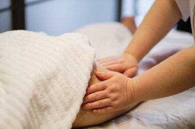 Vücut bakımı konsepti. Özel anti-elülit tedavisi. Masör spa salonundaki genç bayana antielülit masajı yapıyor. Görüntüyü kapat
