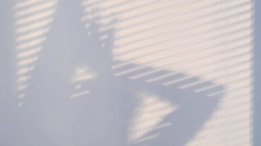 Panjurlar ve kadın silueti ile kapatılmış bir pencerenin gölgesi duvarda. Bulanık karanlık gölgeler duvarda hareket ediyor..