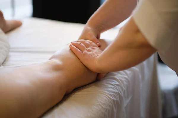 Detail van handen masseren menselijke kuitspier Therapeut uitoefenen druk op vrouwelijke been. Handen van massage therapeut masseren benen van jonge vrouw in spa salon. Lichaamsverzorging in spa salon voor jonge vrouw. — Stockfoto