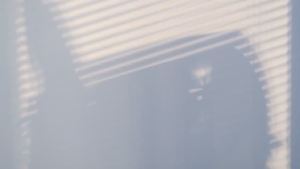 Sombras na parede de uma janela fechada com persianas e uma silhueta de mulheres. Sombras escuras desfocadas movendo-se na parede. movimento de sombra. Vídeo em câmara lenta. imagens de stock — Vídeo de Stock
