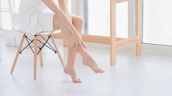 Kvinna röra sin släta och mjuk hud på benen, njuta av skönhetsbehandlingar. ung asiatisk kvinna applicera kräm och lotion röra foten torr på sängen. Kopiera utrymme. — Stockfoto