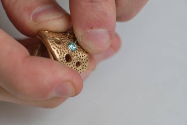 Makro atış. Mücevher yapımı. Yüzük tamir ediliyor. Elması yüzüğe takıyorum. Profesyonel aletlerle mücevher yapımı için masaüstü.