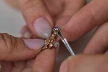 Makro atış. Mücevher yapımı. Yüzük tamir ediliyor. Elması yüzüğe takıyorum. Profesyonel aletlerle mücevher yapımı için masaüstü.