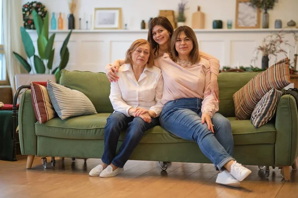 Три поколения женщин сидят вместе на диване. бабушка, дочь и внучка позируют вместе, чтобы сделать совместное фото. — стоковое фото