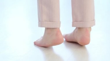 Tanınmayan kadın bacakları, çıplak ayaklı kız modern evin içinde sıcak ahşap zeminin keyfini çıkarıyor. Yumuşak odaklanma. Yavaş çekim videosu. depolama görüntüleri