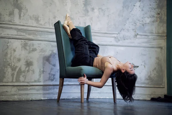 Sandalyede poz veren genç ve güzel bir kadın. Kotlu bir balerin portresi