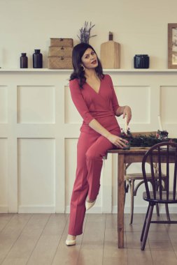 Düşüncelere dalmış güzel bir esmer kadının portresi. Güzel, genç ve güzel bir kadın. Parlak kırmızı rujdan yapılmış parlak bir akşam makyajı. Zarif takım elbise kırmızı pantolon bluz ceket yüksek topuklu ayakkabılar parti için..