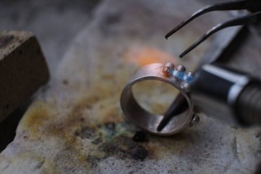 Macro shot. Craft jewelery making with professional tools. A handmade jeweler process, manufacture of jewellery. Melting metal clipart