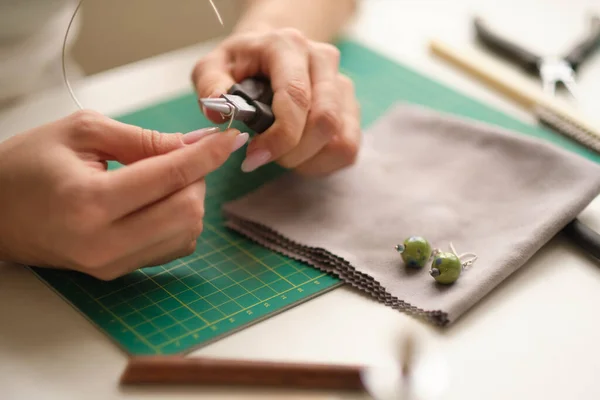 Mujer usando alicates para ajustar las gemas de malaquita. Joyería artesanal con herramientas profesionales. Un proceso de joyería hecha a mano, fabricación de joyas. —  Fotos de Stock