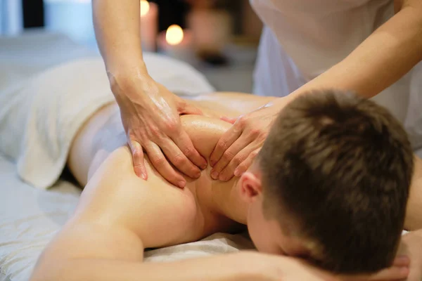 Primer plano del hombre disfrutando en relajantes hombros masaje. Hombre relajante en mesa de masaje recibiendo masaje — Foto de Stock
