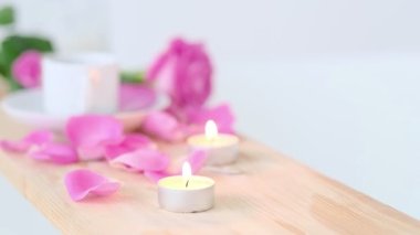 Pembe mum ve ahşap arka planda çiçekler olan güzel bir spa ortamı. Salonda spa tedavisi kavramı. Rahatlama, huzur ve zevk atmosferi. Lüks yaşam tarzı.