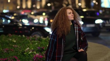 Güzel, genç, şık bir kadın gece caddelerinde yürüyor. Dışarda olumlu bir portre.