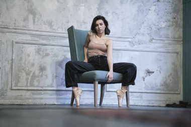Sandalyede poz veren genç ve güzel bir kadın. Kotlu bir balerin portresi