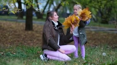 Mutlu anne kızıyla birlikte sonbahar parkında yürüyor. Aile sonbahar parkında yürüyor. Mutlu çocukluk kavramı