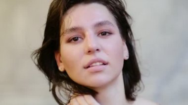 Stüdyoda kameraya bakan gülümseyen genç kızı kapat. Kıvırcık saçlı manken yüzü gülümsüyor. Neşeli kızın portresi, açık gözler. Kadın doğası güzelliği. yumuşak, odaklanmış, çözülmüş