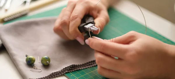 Mujer usando alicates para ajustar las gemas de malaquita. Joyería artesanal con herramientas profesionales. Un proceso de joyería hecha a mano, fabricación de joyas. —  Fotos de Stock