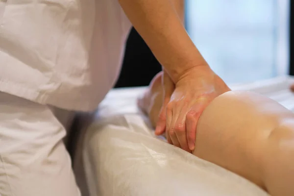 Detalhe das mãos massageando o músculo da panturrilha humana.Terapeuta aplicando pressão na perna feminina. Mãos de massagista massagista massageando pernas de mulher jovem no salão de spa. Cuidados com o corpo no salão de spa para mulher jovem. — Fotografia de Stock