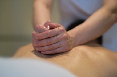 İnsanın rahatlatıcı omuz masajından zevk aldığı yakın çekim. Masaj masasında dinlenen adam masaj yaptırıyor.