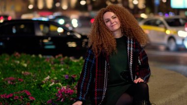 Güzel, genç, şık bir kadın gece caddelerinde yürüyor. Dışarda olumlu bir portre.