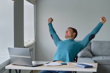 Yapılan işten memnun. Evinden çalışan bir adam elleri başının üstünde bir dizüstü bilgisayara bakarken şaşırdı. Oturma odasında sıcak bir atmosferi olan bir kanepede oturdu..