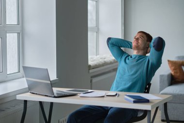 Yapılan işten memnun. Evinden çalışan bir adam elleri başının üstünde bir dizüstü bilgisayara bakarken şaşırdı. Oturma odasında sıcak bir atmosferi olan bir kanepede oturdu..