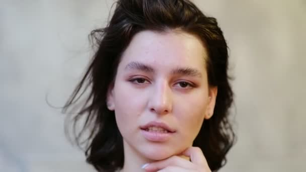 Nahaufnahme Junge lächelnde Frau, die im Studio in die Kamera schaut. Lockiges Haar Modelgesicht lächelnd. Porträt eines fröhlichen Mädchens mit offenen Augen. Weibliche Naturschönheit. Weich, fokussiert, defokussiert — Stockvideo