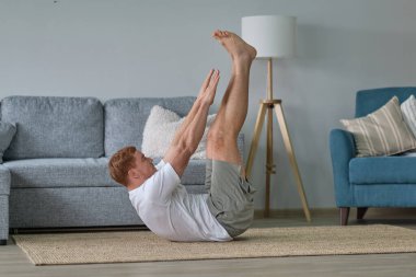 Genç aktif adam dizüstü bilgisayarda video eğitimi izliyor, egzersiz yapıyor, sabah evde egzersiz yapıyor. Spor, sağlıklı yaşam tarzı. Evde Forma gir.