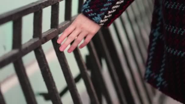 Nierozpoznawalna kobieta idzie ulicą i dotyka ogrodzenia dłonią. — Wideo stockowe