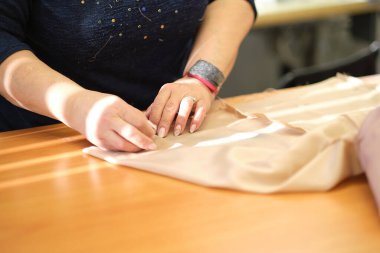 Elbise dikmek için tekstil işinde çalışan yetenekli bir kadın terzi. Dikiş işleminin görüntüsünü kapat. Işık bulanık arkaplan