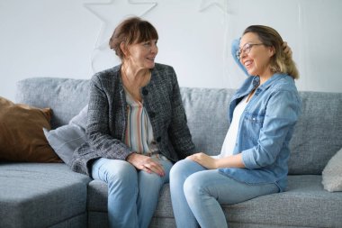 Evde yaşlı bir anne ve yetişkin bir çocuk gülümsemesi. gelinim kayınvalidem. Yaşlı anne ve orta yaşlı kızın birlikte gülümseyen portresi.