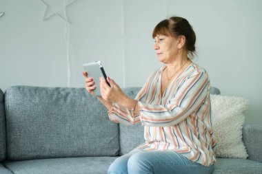 Evde dijital tablet kullanan yaşlı Hintli kadın. Büyükannem torunlarına ya da arkadaşlarına video görüşmeleri yapıyor.