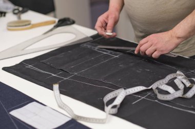 Terzi kadın işyeri. Terzi kadın, terzi stüdyosunda elbise dikmek için tebeşirle desen çiziyor. Terzi atölyesi, el yapımı özel elbiseler dikmek ve tamir etmek. yaratıcı meslek kavramı