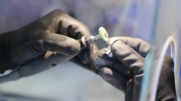 Ręce jubilera pracujące z pierścionkiem. Ten film pokazuje ręce jubilera czyszczące pierścień za pomocą narzędzia obrotowego. — Wideo stockowe