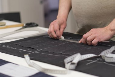 Terzi kadın işyeri. Terzi kadın, terzi stüdyosunda elbise dikmek için tebeşirle desen çiziyor. Terzi atölyesi, el yapımı özel elbiseler dikmek ve tamir etmek. yaratıcı meslek kavramı