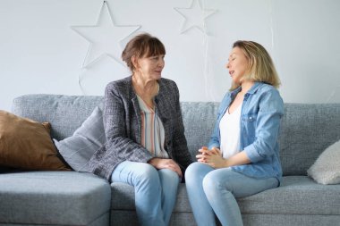 Evde yaşlı bir anne ve yetişkin bir çocuk gülümsemesi. gelinim kayınvalidem. Yaşlı anne ve orta yaşlı kızın birlikte gülümseyen portresi.