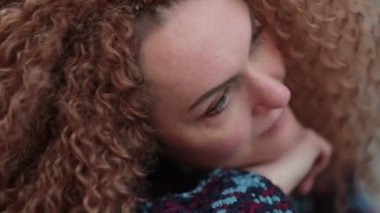 Güzel genç bir kadın kameraya bakıyor ve neşeyle gülümsüyor. Gün ışığında sokakta gülen surat. Dışarıda olumlu bir portre var. Kapatın. Yavaş çekim videosu. depolama görüntüleri