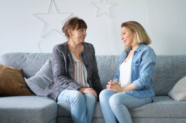 Evde yaşlı bir anne ve yetişkin bir çocuk gülümsemesi. gelinim kayınvalidem. Yaşlı anne ve orta yaşlı kızın birlikte gülümseyen portresi.