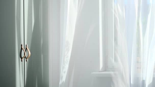 Soleil du matin brillant dans la fenêtre ouverte à travers les rideaux. Rideau d'agitation blanc abstrait dans un appartement de chambre à coucher blanche. — Video