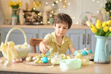 Küçük çocuk renkli yumurtaları hasır bir Paskalya sepetine koyar. Paskalya hazırlama kavramı