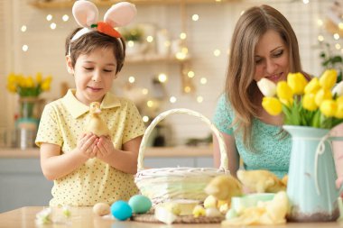 Anne ve oğul birlikte eğleniyor ve ziyafeti kutluyorlar. Aile Paskalya için hazırlanıyor. Little ve annem evi dekore ediyor. yumuşak odak