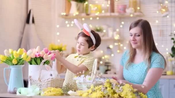 Matka a syn se spolu baví a slaví hostinu. rodina se připravuje na Velikonoce. Malá a máma zdobí domov. měkké zaměření — Stock video
