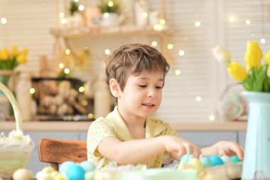Küçük çocuk renkli yumurtaları hasır bir Paskalya sepetine koyar. Paskalya hazırlama kavramı