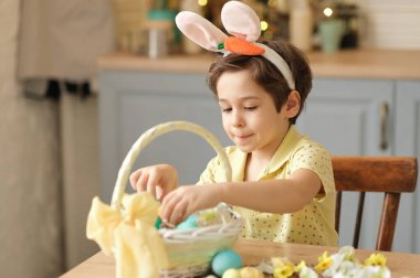 Küçük çocuk renkli yumurtaları hasır bir Paskalya sepetine koyar. Paskalya hazırlama kavramı