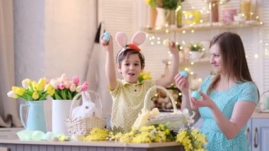 Anne ve oğul birlikte eğleniyor ve ziyafeti kutluyorlar. Aile Paskalya için hazırlanıyor. Little ve annem evi dekore ediyor. yumuşak odak